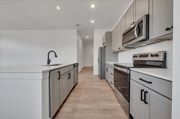 A modern kitchen with a white countertop and stainless steel appliances.